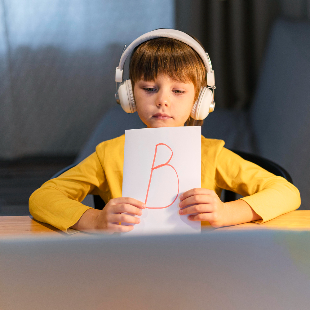 Student holding a tablet while seated at a classroom desk.