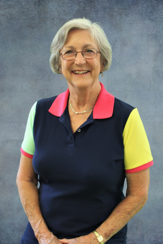 Woman in a polo shirt in front of a gray background.