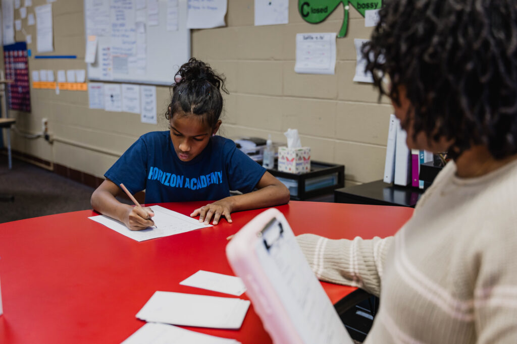 Teacher providing one-on-one support to a student during a classroom activity at Horizon Academy.