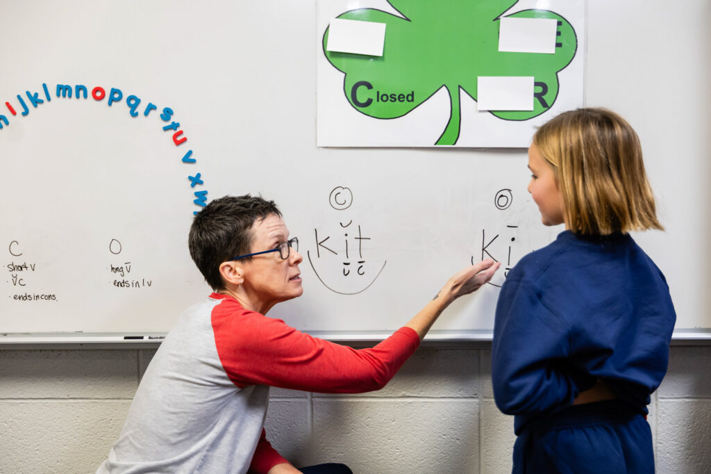 Teacher providing one-on-one instruction using a classroom whiteboard at Horizon Academy.