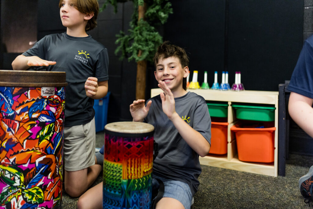 Horizon Academy student playing a hand drum during a music therapy activity.