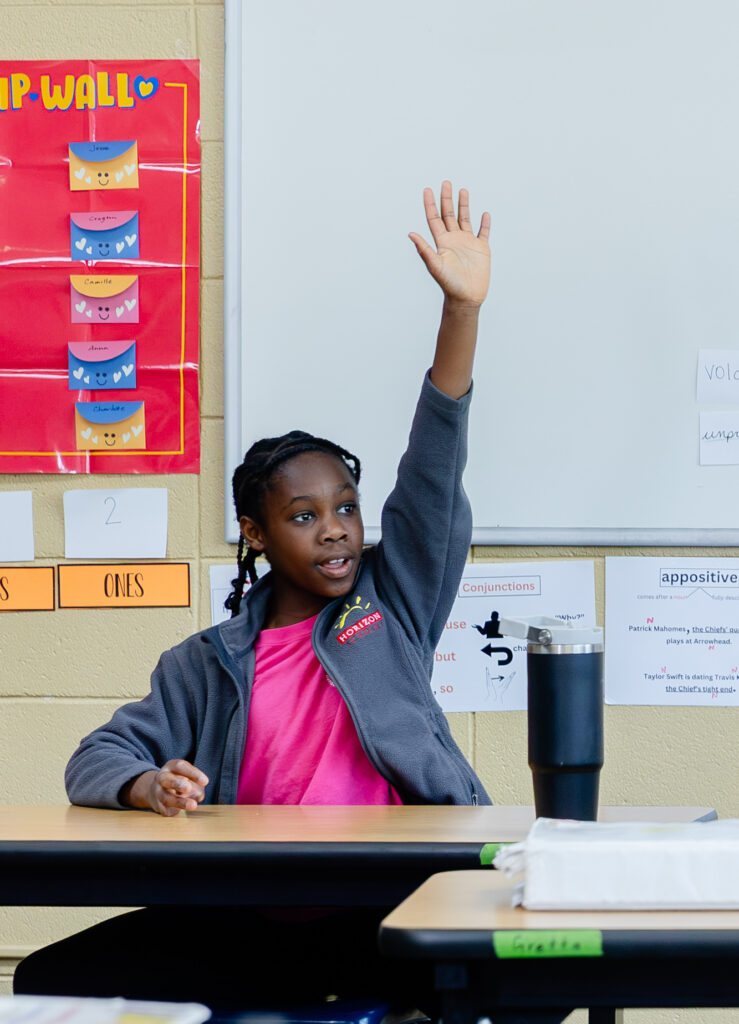 Intermediate school student raising their hand to participate in class.