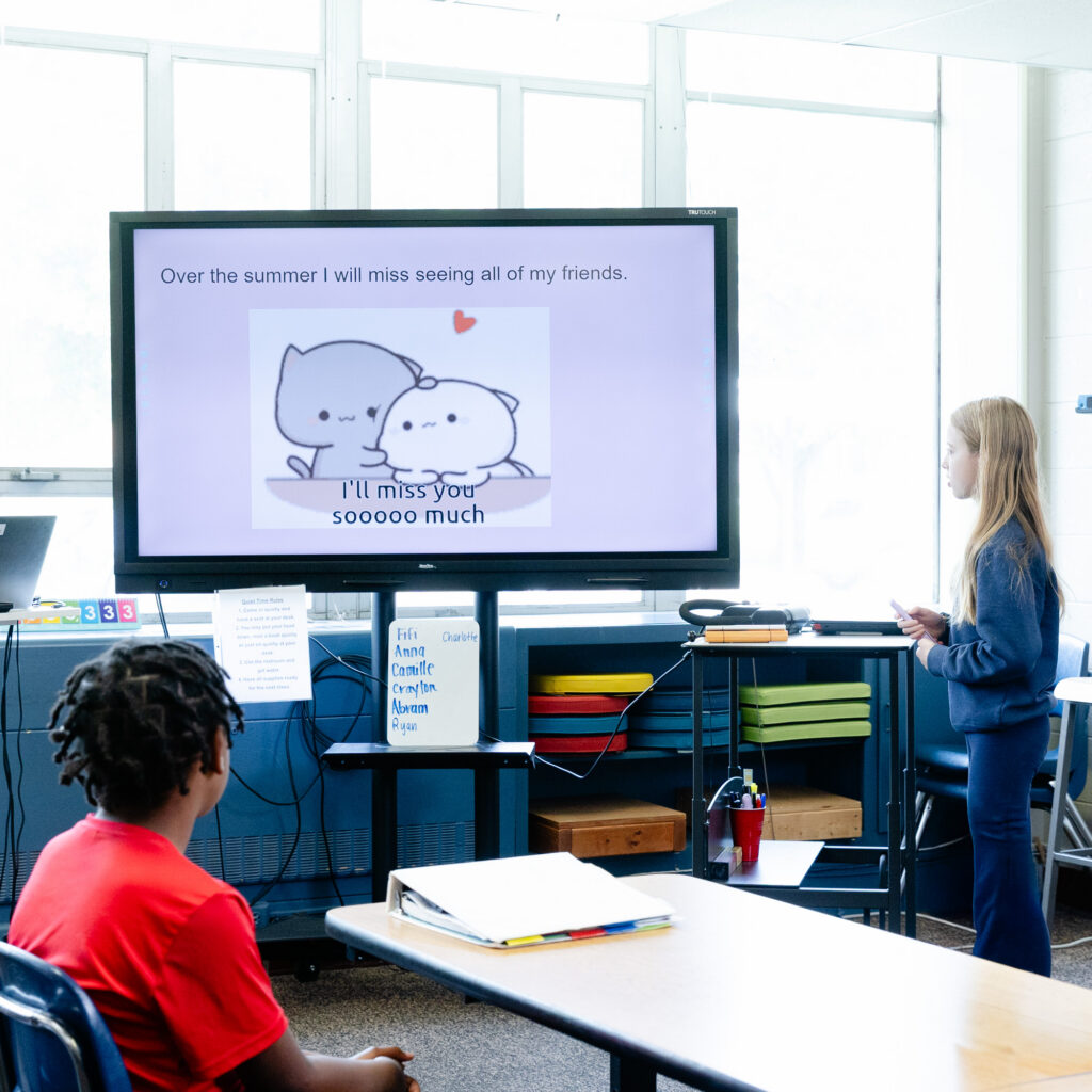 Teacher leading an intermediate school lesson using an interactive classroom display.
