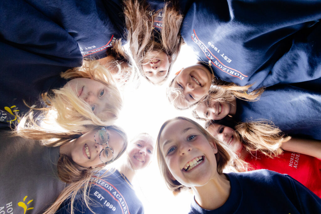 Intermediate school students gathered in a circle during a collaborative outdoor activity.