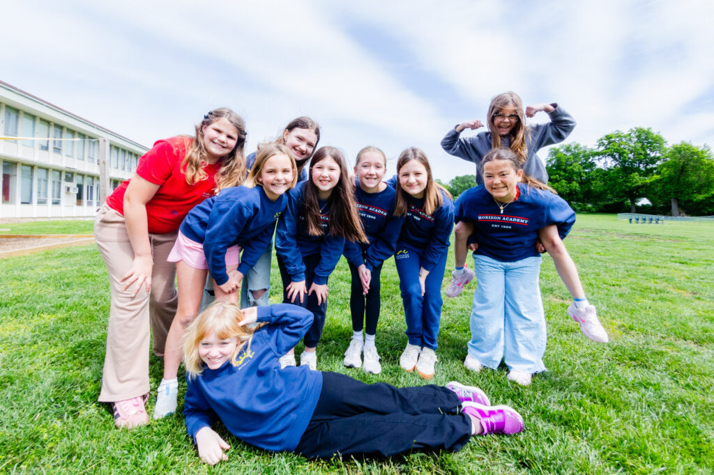 Group of intermediate school students smiling together outdoors on the Horizon Academy campus.
