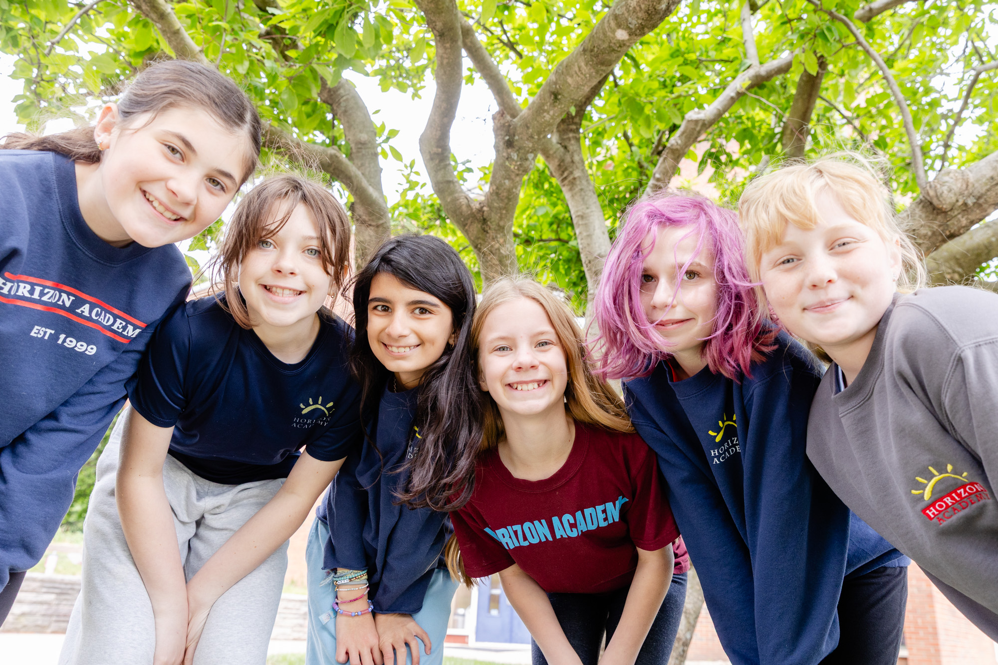 Group of intermediate school students smiling together outdoors on the Horizon Academy campus.