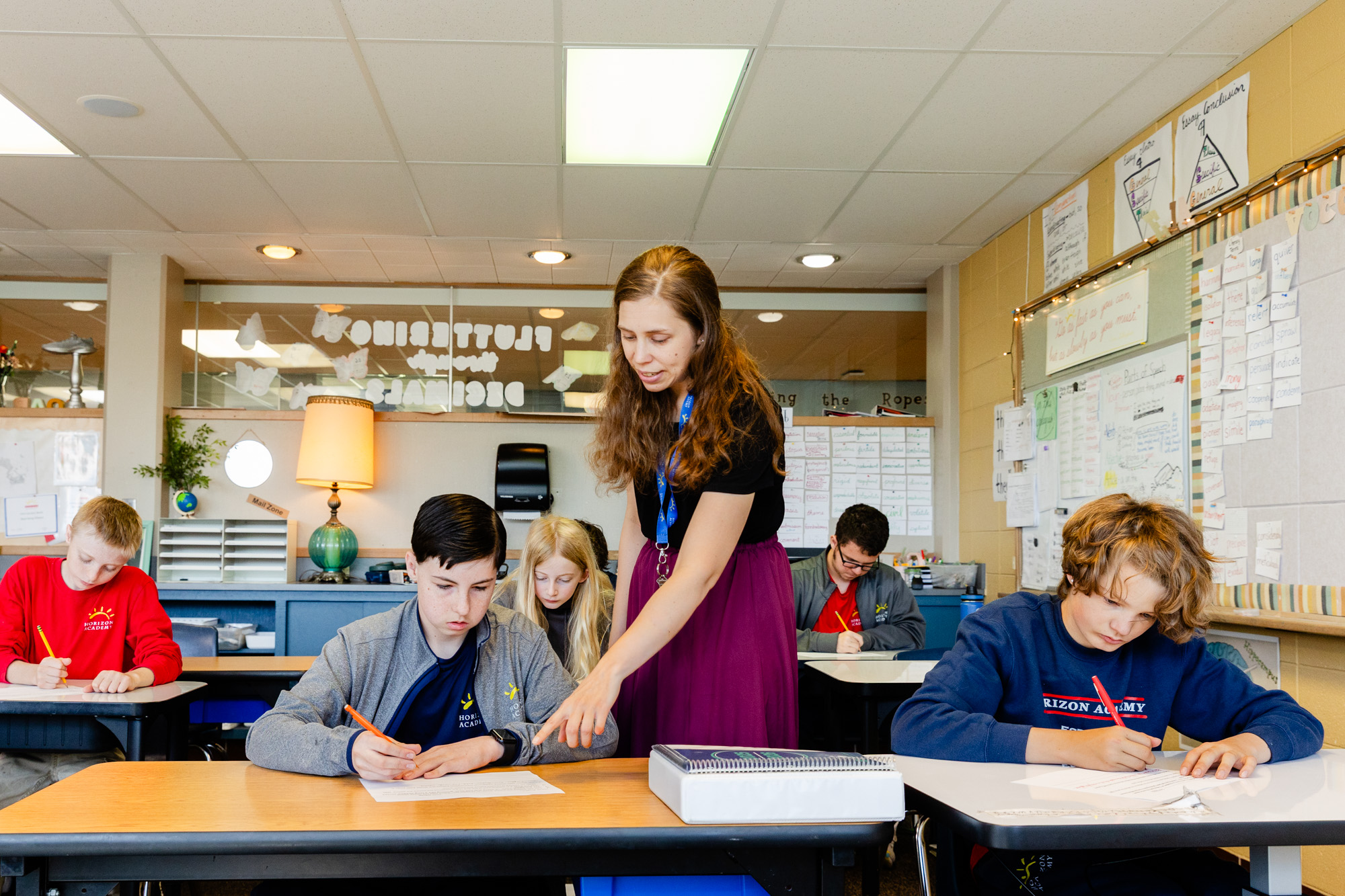 Teacher assisting intermediate school students during a classroom lesson.