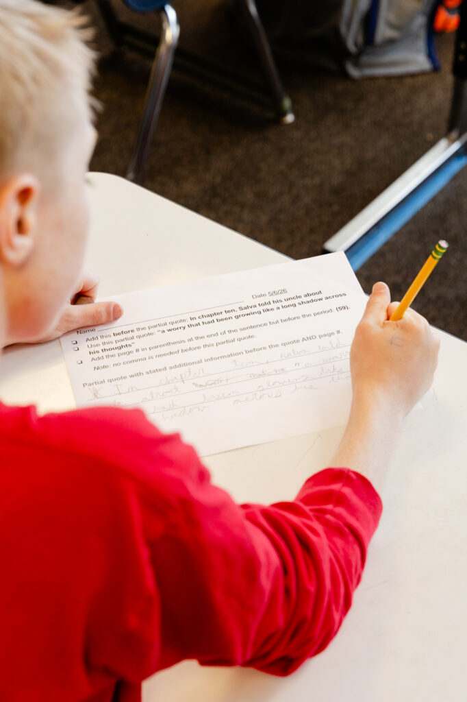 Intermediate school student completing a classroom writing assignment.