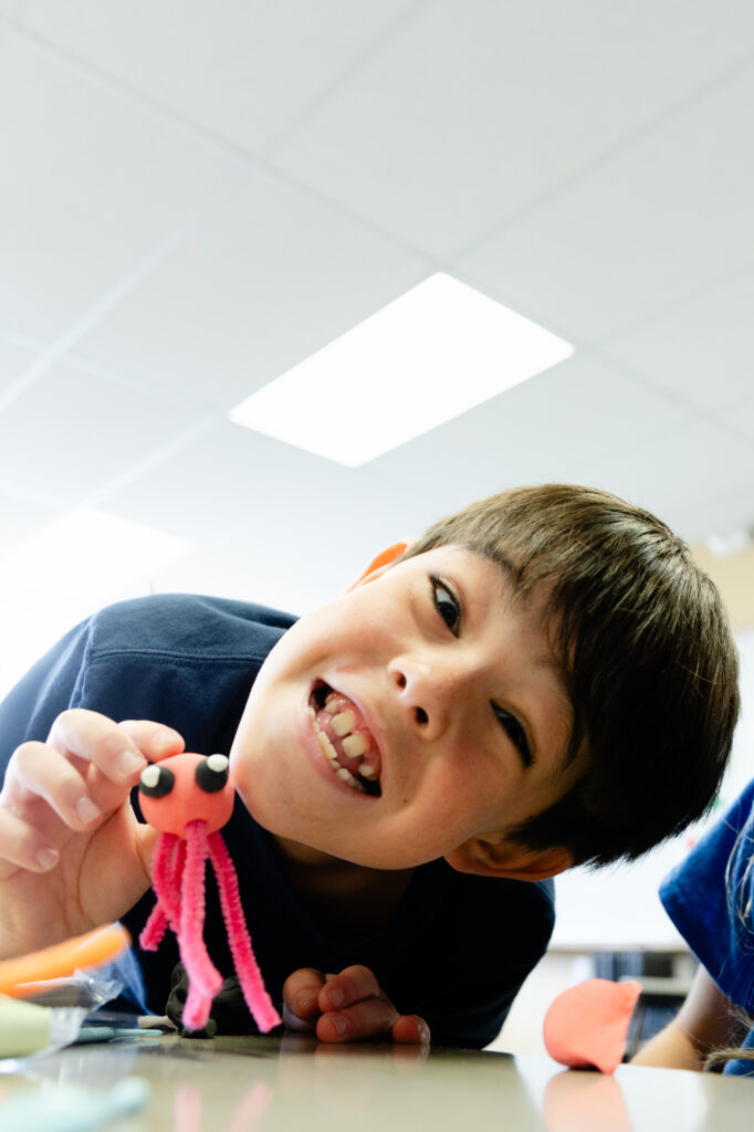 Lower school student smiling while participating in a hands-on classroom activity.