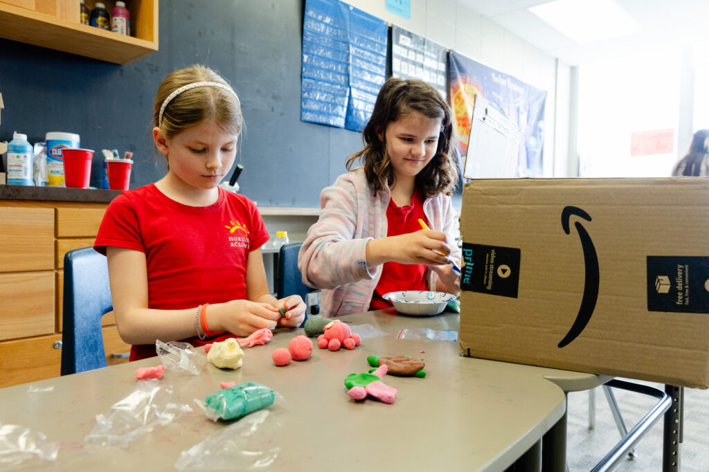 Lower school students creating colorful projects during a classroom activity.