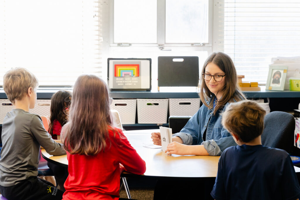 Teacher meeting one-on-one with a lower school student at a classroom table.