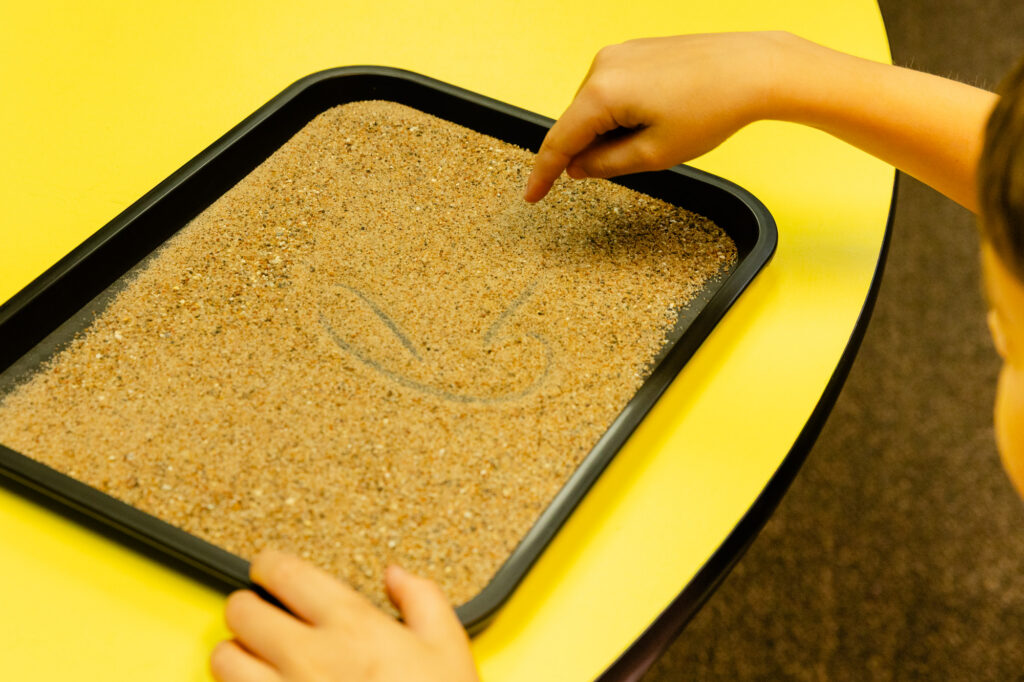 Student using a sensory sand tray as an instructional learning tool at Horizon Academy.