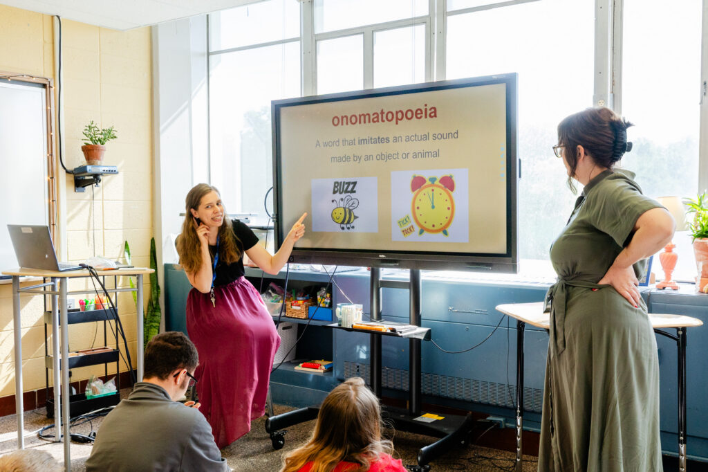 Teacher leading a middle school classroom lesson using a large interactive display.