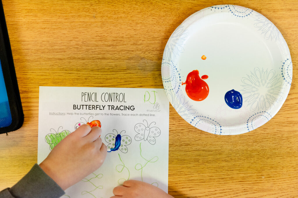 Fine motor activity using a worksheet and colored manipulatives during occupational therapy.