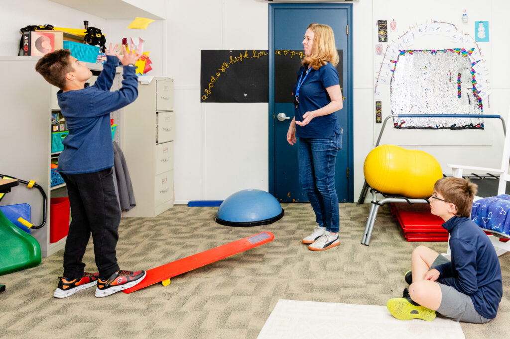 Occupational therapist guiding a student through a balance and movement activity.