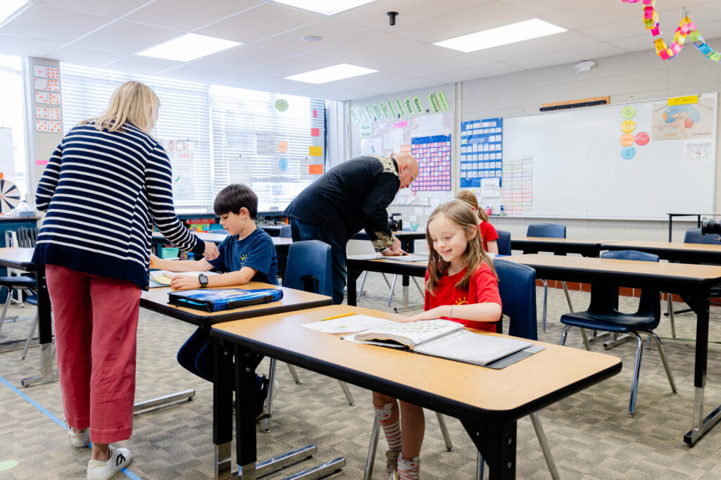 Educator assisting students during a classroom learning activity.