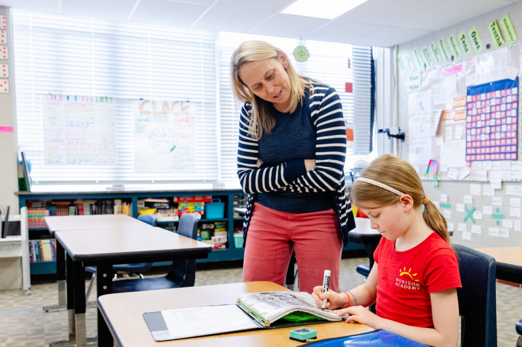 Educator providing one-on-one support to a student during a classroom activity.