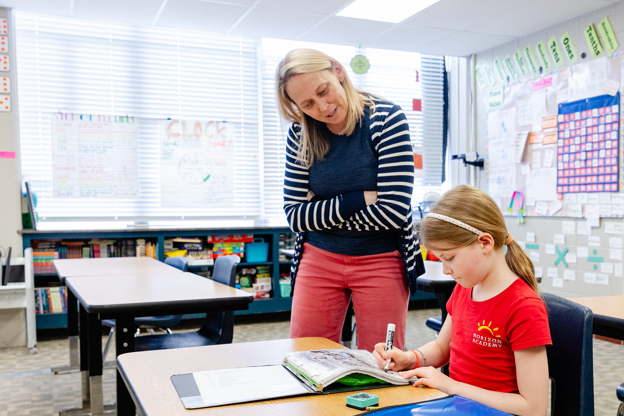 Educator providing one-on-one support to a student during a classroom activity.