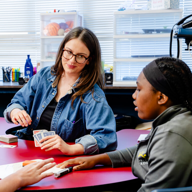 Educator providing individualized support to a student during a classroom activity.