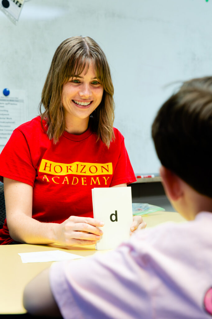 Tutor smiling while providing one-on-one academic support to a student.