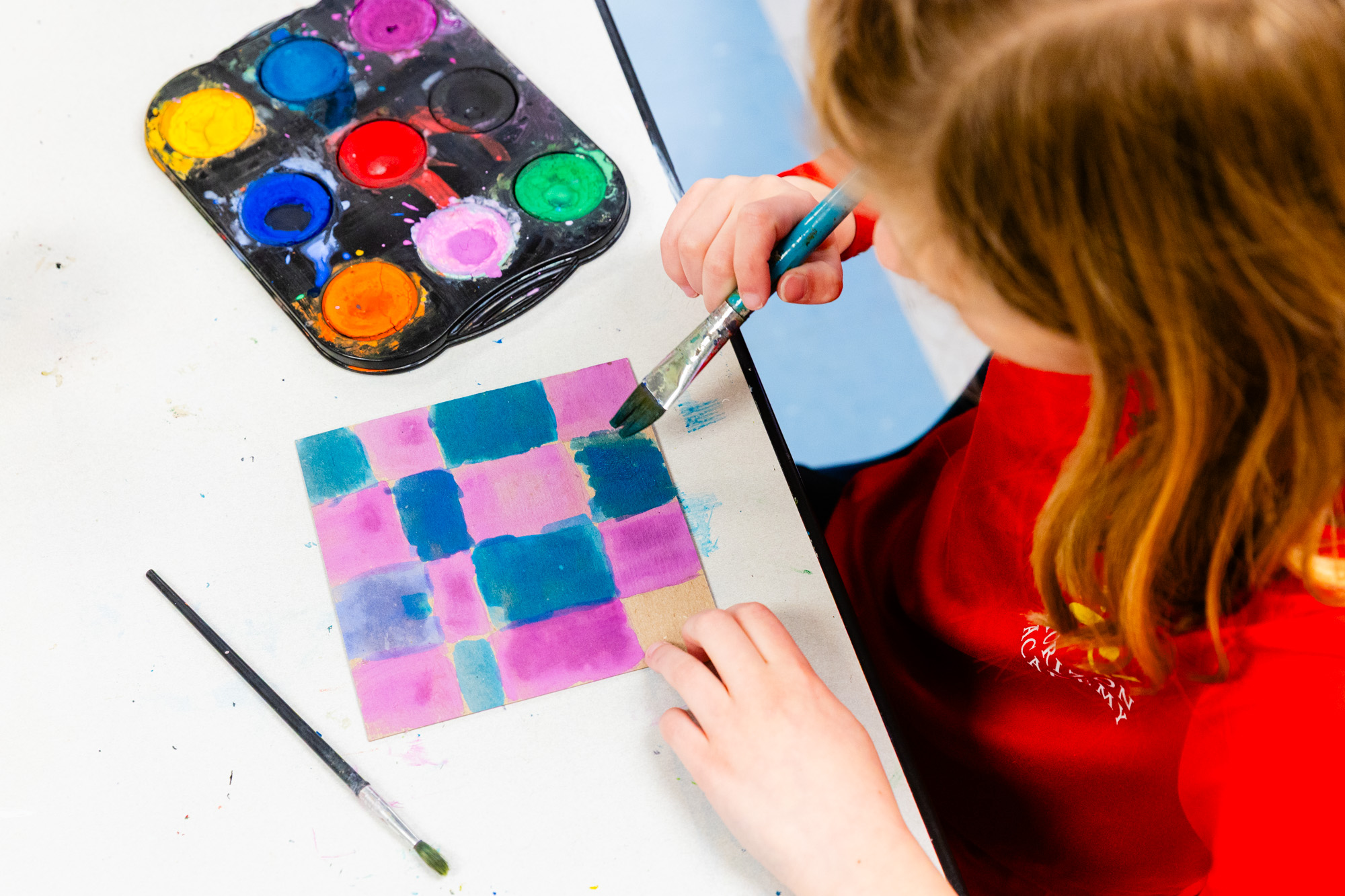 Student painting with watercolors during a classroom art activity.