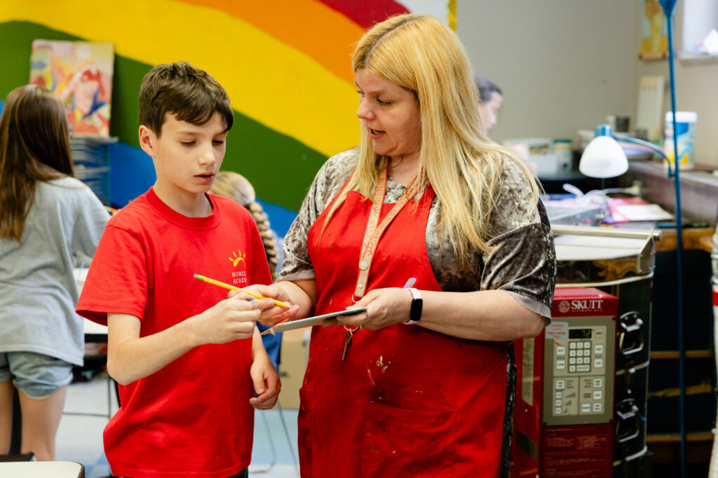 Staff member assisting a student during a classroom learning activity.