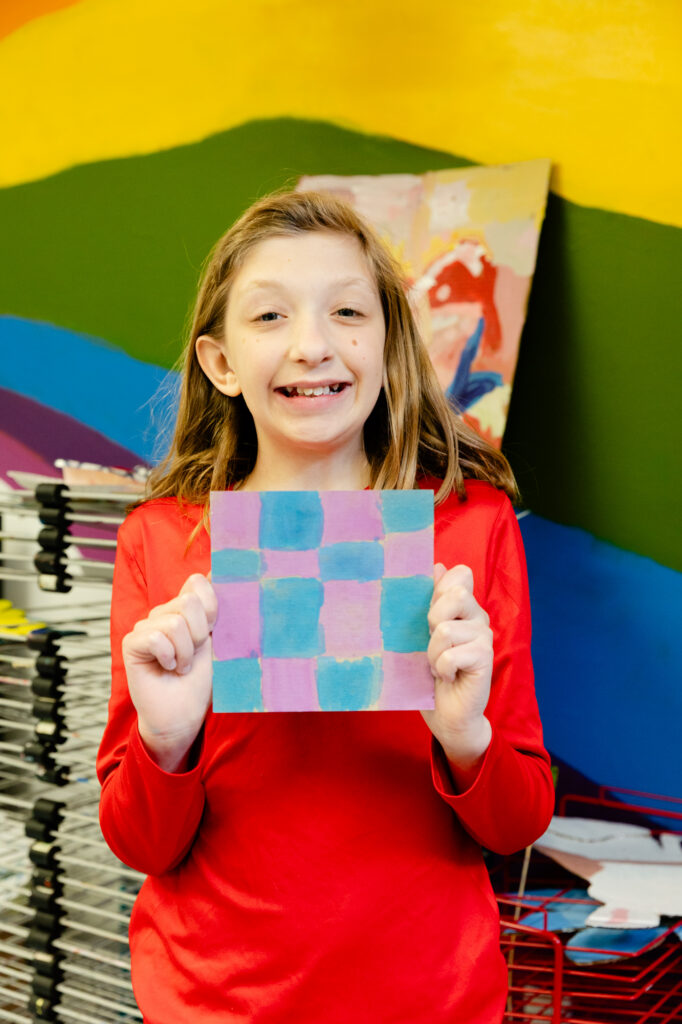 Student smiling while holding a completed classroom project.