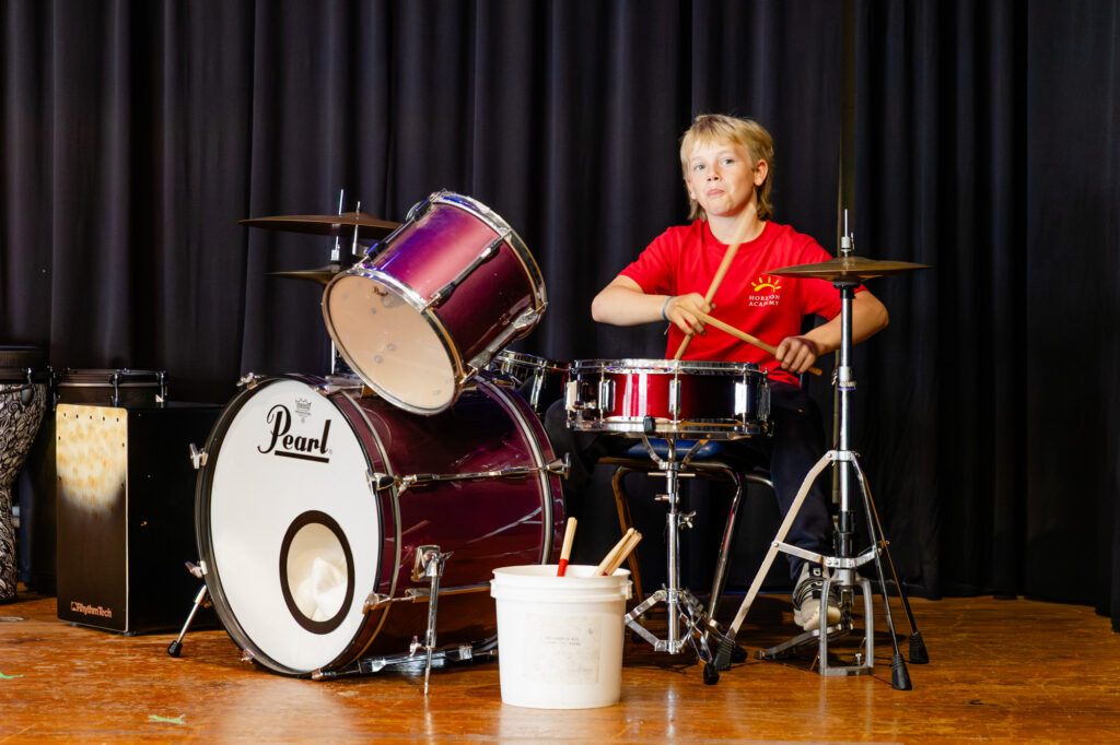 Student playing a drum during a music performance at Horizon Academy.