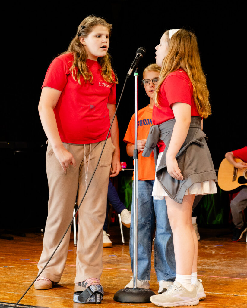 Staff member speaking with a student during a stage presentation at Horizon Academy.