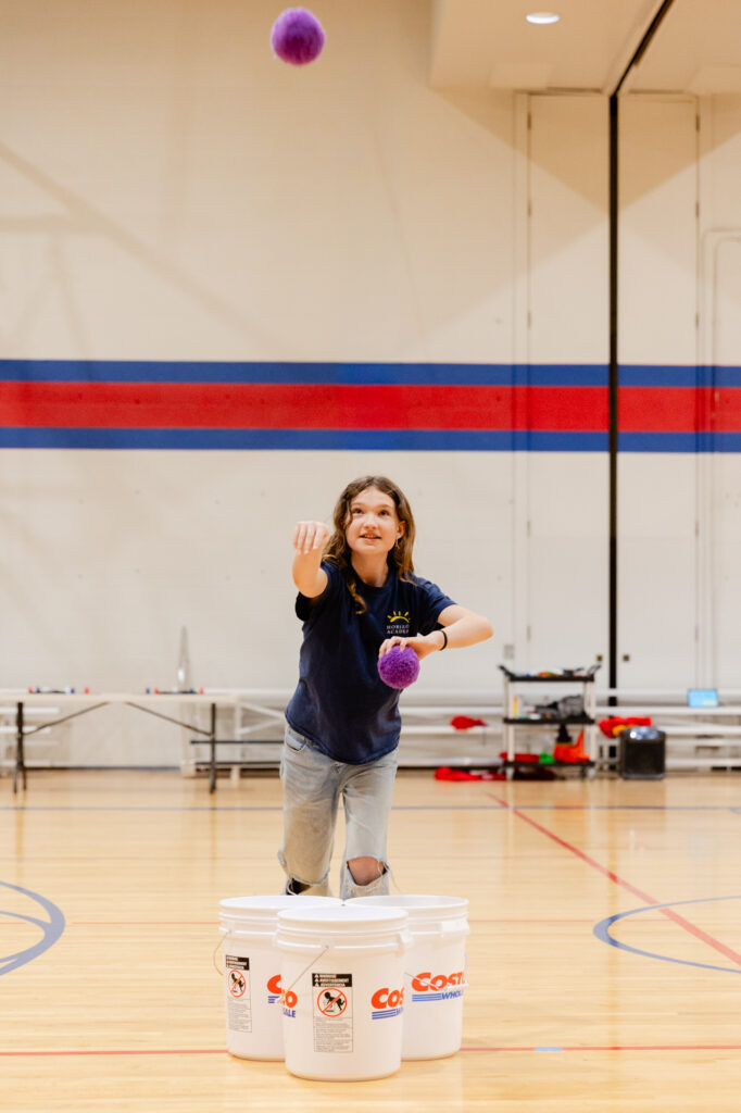 Staff member leading a student activity in the Horizon Academy gymnasium.