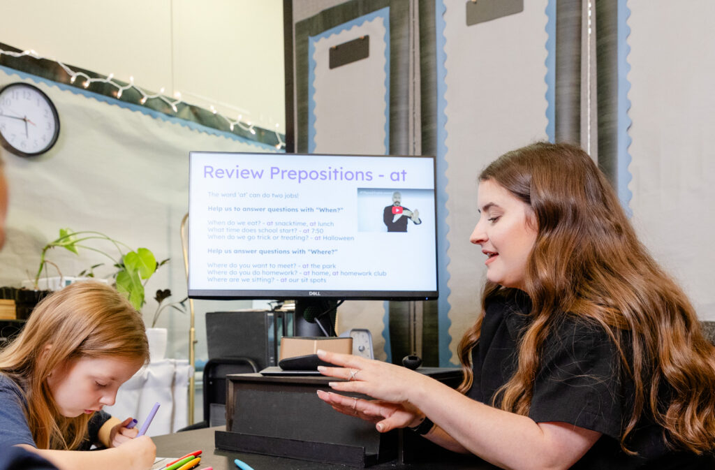 Speech-language pathologist using a computer display during a therapy session with a student.
