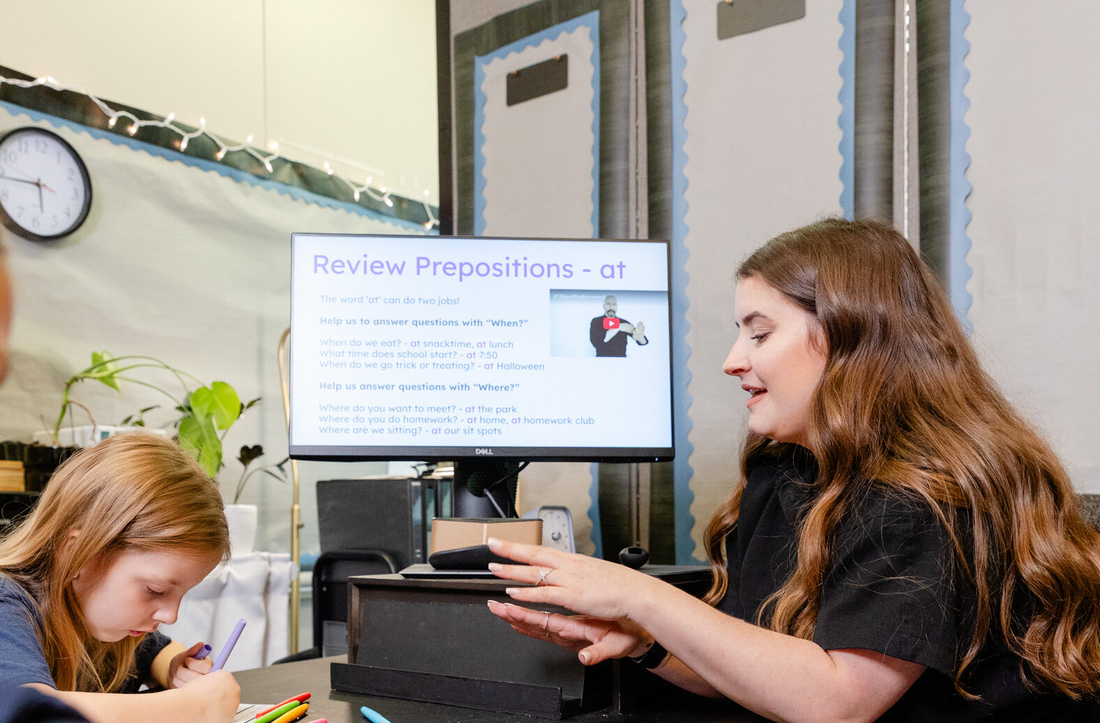 Speech-language pathologist using a computer display during a therapy session with a student.