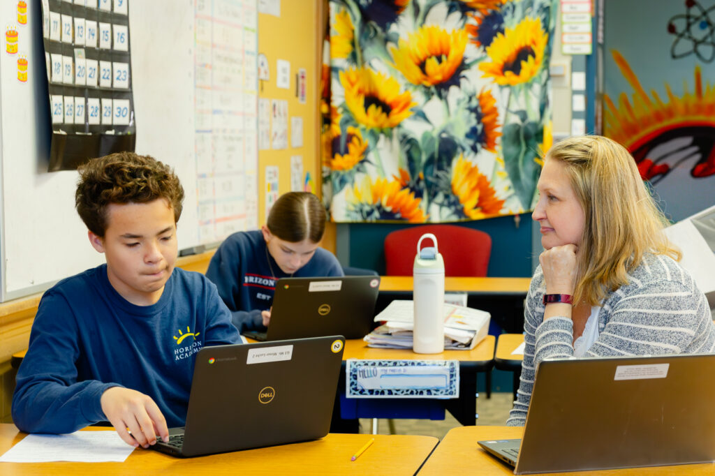 Students working together on laptops during a classroom lesson at Horizon Academy.