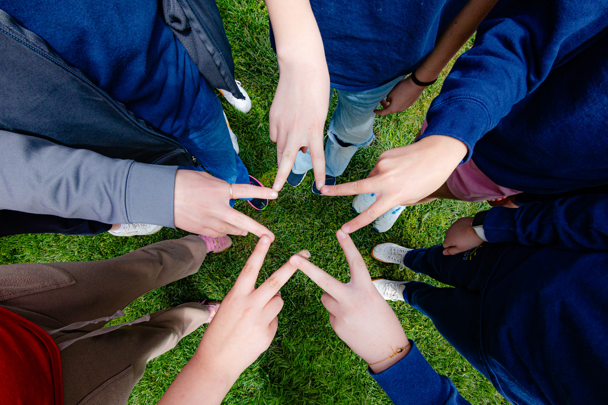 Students placing their hands together in a circle during a team-building activity.