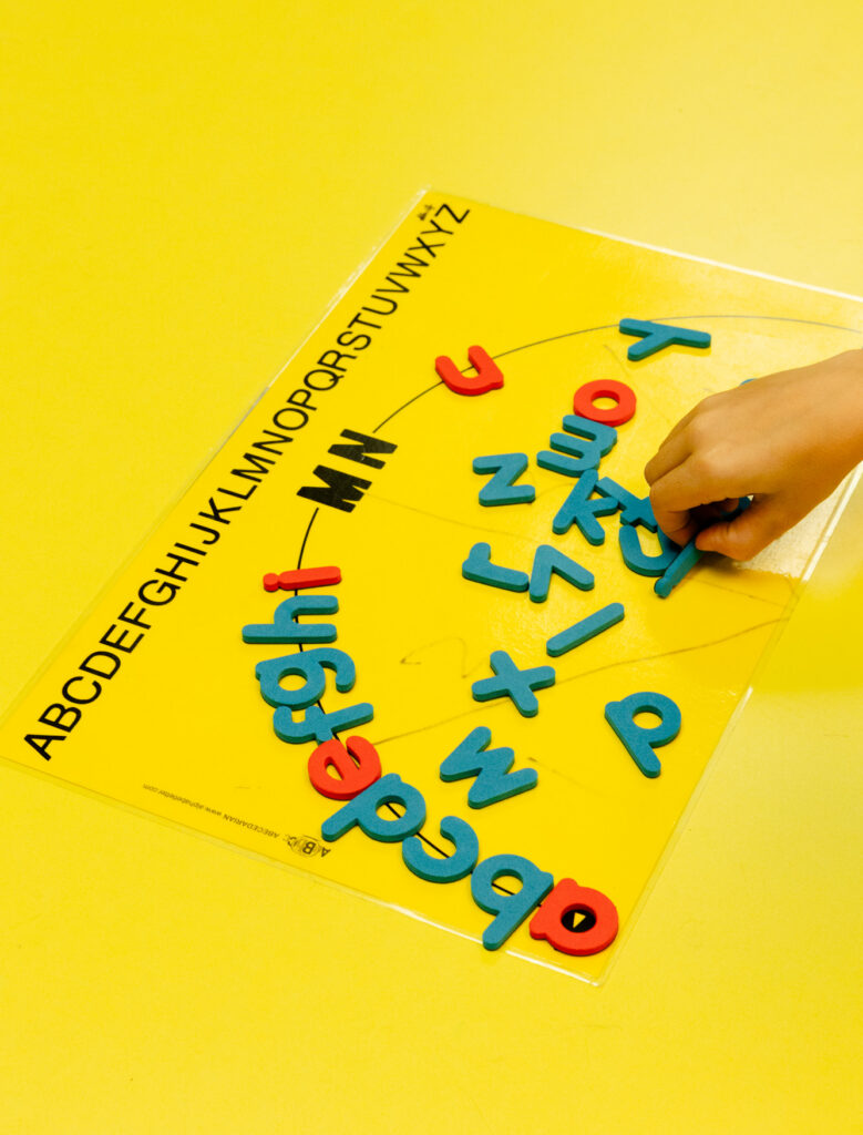 Child arranging magnetic letters during a literacy learning activity.
