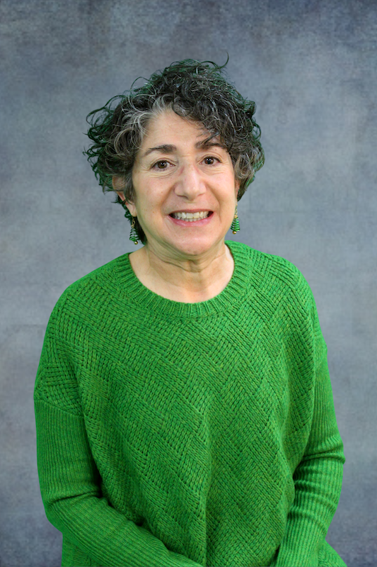 Woman in green shirt in front of gray background.