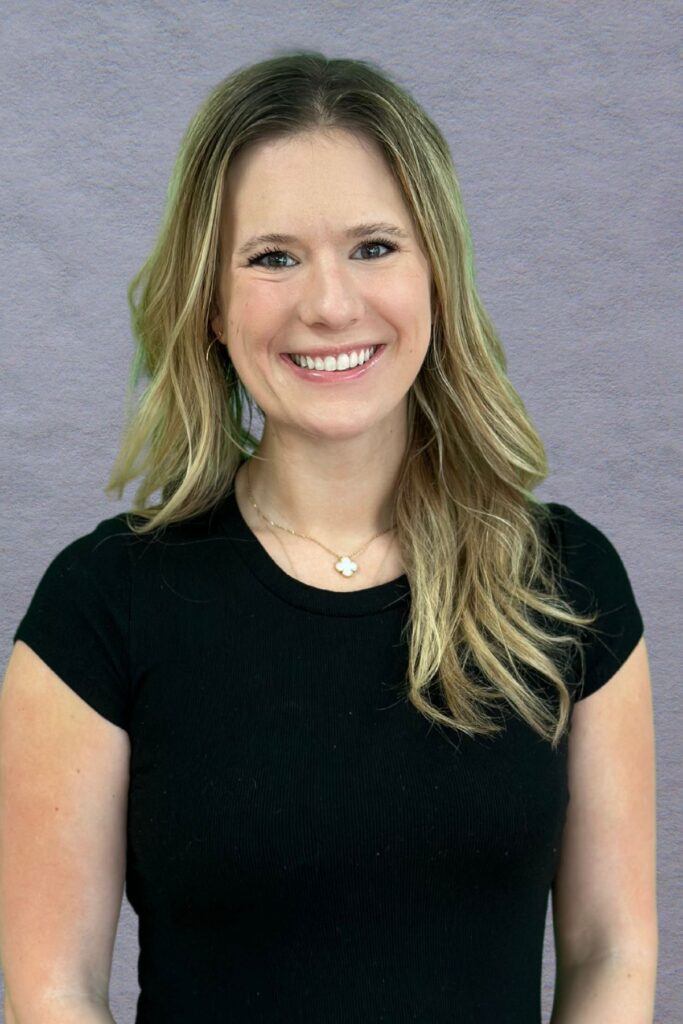 Woman in black shirt with long hair in front of gray background.