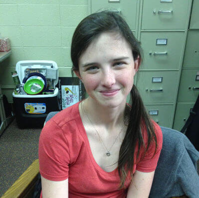 Young woman wearing a red shirt in front of filing cabinets.