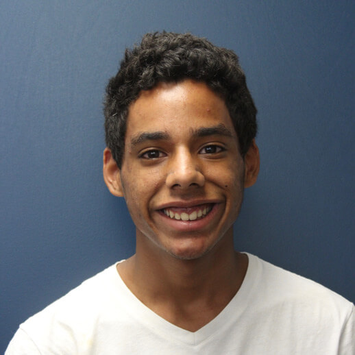Young man in white shirt standing in front of a blue background.
