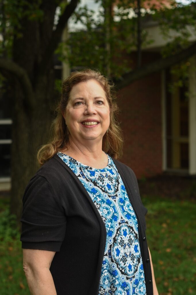 Linda Cummings smiling outdoors near a campus building at Horizon Academy.