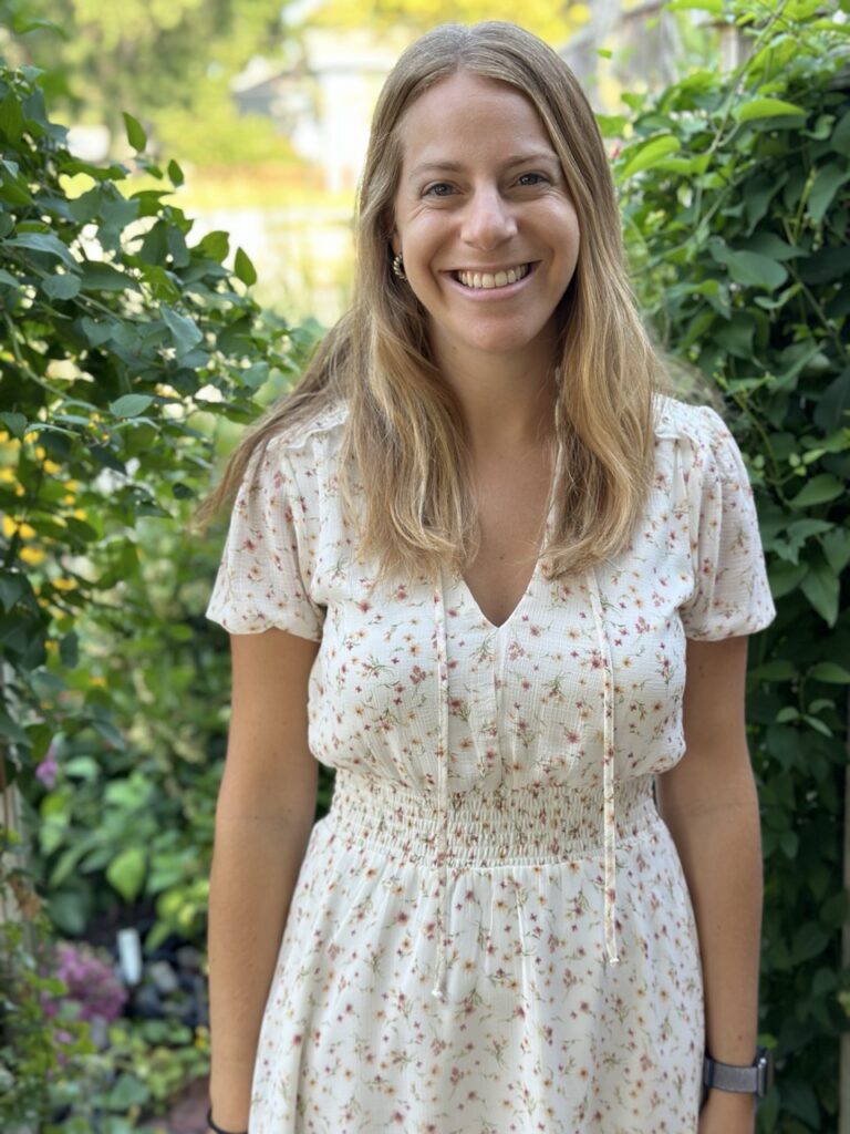 Staff member standing outdoors wearing a light-colored floral dress at Horizon Academy.