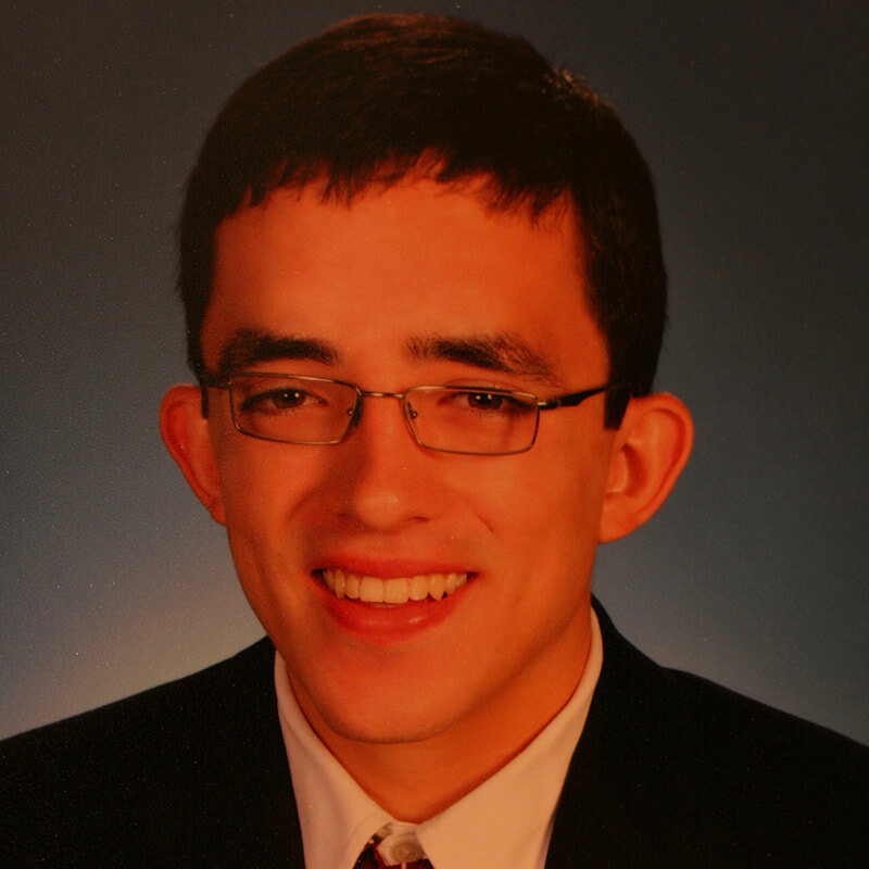 Headshot of young man in glasses smiling.
