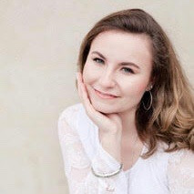Young smiling woman in front of beige background.