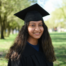 Young graduate wearing cap and gown outside.