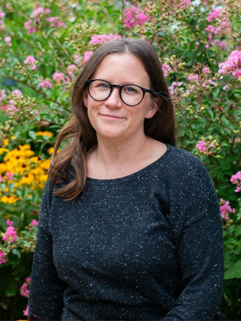 Staff member pictured in front of flower bushes on the Horizon Academy campus.
