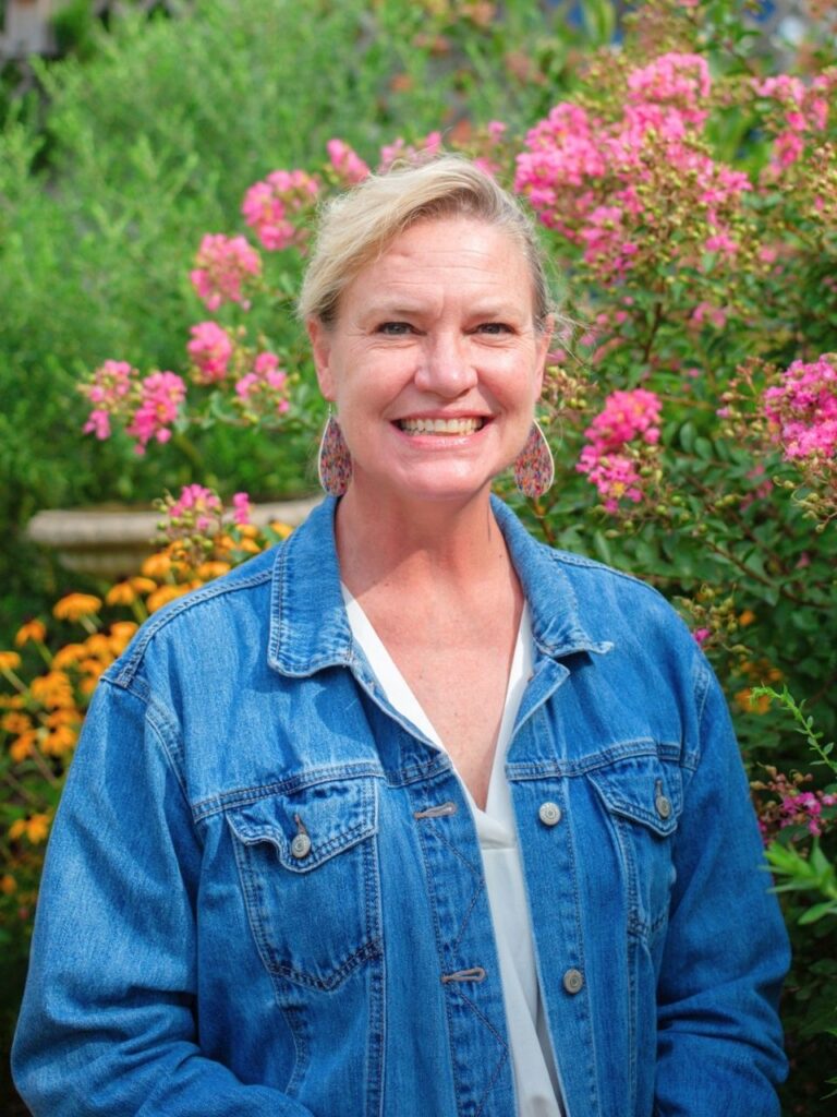 Staff member pictured in front of flower bushes on the Horizon Academy campus.