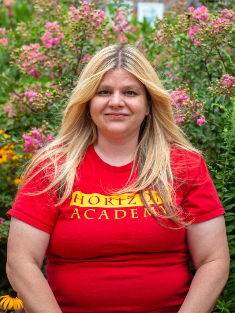 Staff member pictured in front of flower bushes on the Horizon Academy campus.