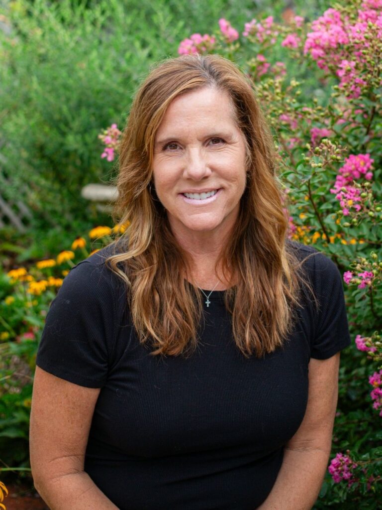 Staff member pictured in front of flower bushes on the Horizon Academy campus.