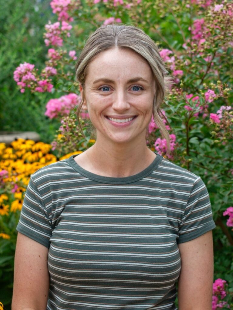 Staff member pictured in front of flower bushes on the Horizon Academy campus.