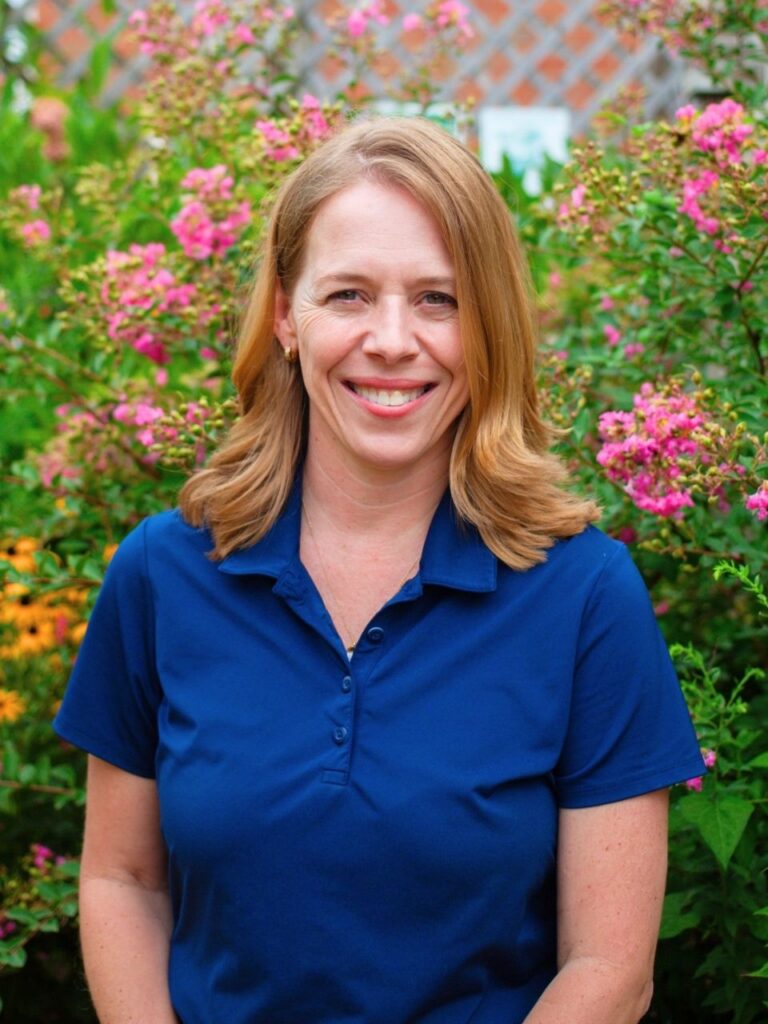 Staff member pictured in front of flower bushes on the Horizon Academy campus.
